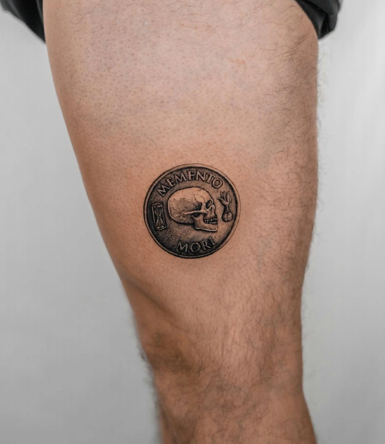 memento mori coin tattoo: A tattoo featuring a coin with "memento mori" inscribed, possibly styled after ancient Roman coins.