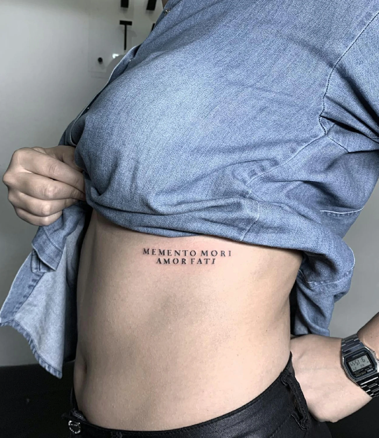 memento mori amor fati tattoo: A tattoo combining the phrases "memento mori" and "amor fati," possibly integrating symbols like a skull and a heart or an infinity sign.