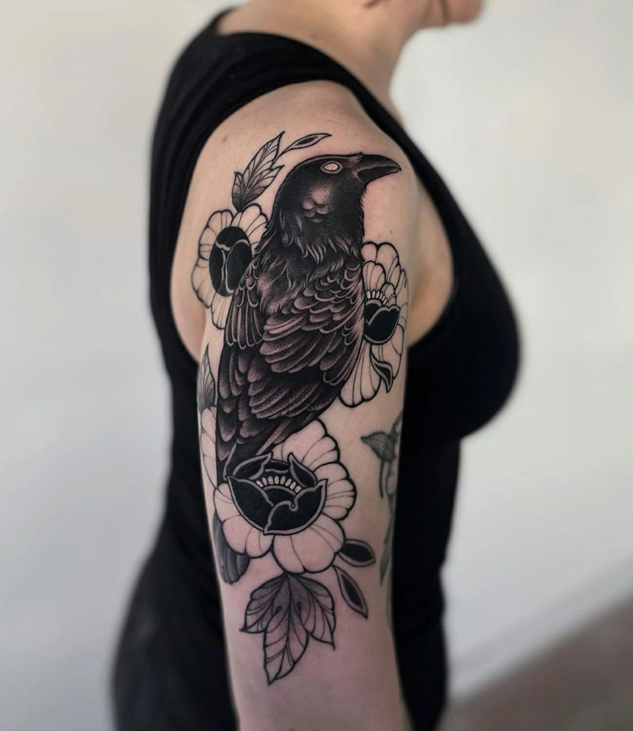 Black raven tattoo: A classic raven tattoo rendered entirely in black ink.